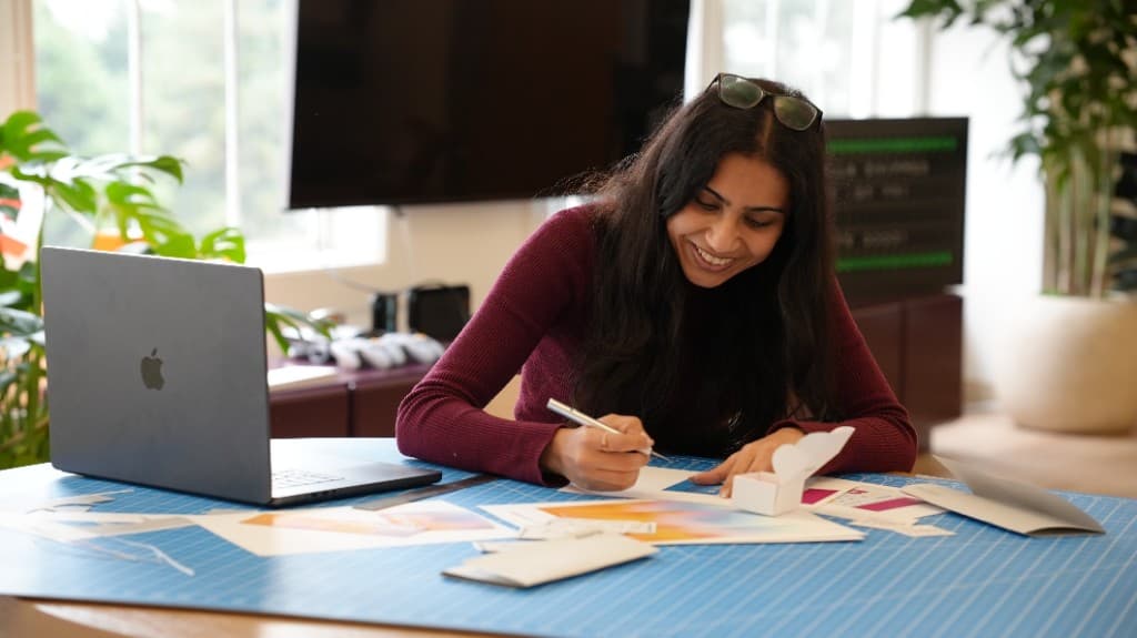 A Gumlooper marking up printed design work at a desk